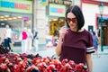 Concentrated young woman buying berries on a street market. Royalty Free Stock Photo