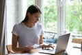 Concentrated young woman paying utility bills online.