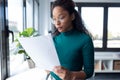 Concentrated young woman reading some documents standing next to the window in the office Royalty Free Stock Photo