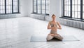 Concentrated young woman in stylish beige tracksuit does padma asana with namaste mudra meditating
