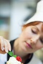 Concentrating head chef putting mint leaf on little cake Royalty Free Stock Photo