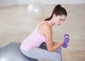 Concentrating on her workout. Profile shot of a young woman lifting a dumbbell with one arm.