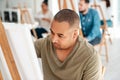 Concentrating on my artwork. a handsome young artist sitting and painting during an art class in the studio. Royalty Free Stock Photo