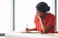 Concentrating young African American female entrepreneur writing in her notebook