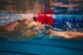 Concentration. Competitive young man, swimming athlete in goggles and red cap in motion, training in pool indoors. Royalty Free Stock Photo