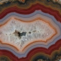 Concentric layers of agate in vibrant red, orange, and grey encircle a central crystalline Royalty Free Stock Photo