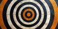 A concentric target pattern with orange, black, and white circles on a tile surface view from above Royalty Free Stock Photo