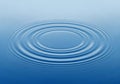Concentric water ripples spread outward on a calm blue water Royalty Free Stock Photo