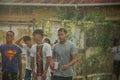 Closeup group of teenagers walks by under tropical rain on dominican city street