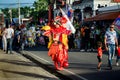 Man in shiny orange costume walks by city street full of people dominican carnival