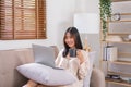 Concept of activity in living room, Asian woman surfing social media on laptop and drinking coffee