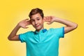 The concept of adolescence and emotions in adolescents. A teenage boy in a blue t-shirt, cheerfully pulling his ears with his