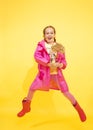 Girls, twin sisters look at each other and laughs on yellow background with flower in hand