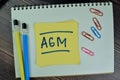 Concept of AGM - Annual General Meeting write on sticky notes isolated on Wooden Table