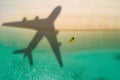 Concept of airplane travel to exotic destination with shadow of commercial airplane flying above beautiful tropical beach. Beach Royalty Free Stock Photo