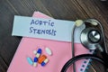 Concept of Aortic Stenosis write on sticky notes with stethoscope isolated on Wooden Table