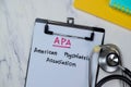 Concept of APA - American Psychiatric Association write on paperwork with stethoscope isolated on Wooden Table