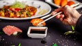 Concept of Asian cuisine. The girl is in a Chinese or Japanese restaurant sushi, holds wooden sticks in his hands. Dunk sushi Royalty Free Stock Photo