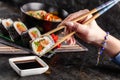 Concept of Asian cuisine. The girl is in a Chinese or Japanese restaurant sushi, holds wooden sticks in his hands Royalty Free Stock Photo