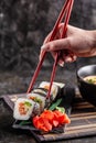 Concept of Asian cuisine. The girl is in a Chinese or Japanese restaurant sushi, holds wooden sticks in his hands. Dunk sushi Royalty Free Stock Photo
