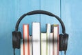 Concept of audio book. headphone and books on blue background