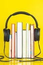 Concept of audio book. headphone and books on yellow background