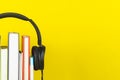 Concept of audio book. headphone and books on yellow background