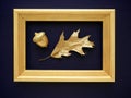 The concept of autumn. Oak leaf and acorn on a dark blue background in a gold frame Royalty Free Stock Photo