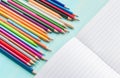 Concept back to school.School accessories, colored pencils, pen with empty notebook on blue wooden background Royalty Free Stock Photo