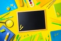 The concept of back to school. The chalk board lies in the center, around it colored pencils, pens, notebooks Royalty Free Stock Photo