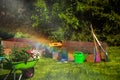 Wheelbarrow with Gardening tools in the garden. watering in the garden. rainbow formation Royalty Free Stock Photo