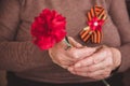 Concept background of May 9 russian holiday Victory Day. Old woman holding in hands a red carnation and St. George`s Royalty Free Stock Photo