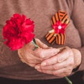 Concept background of May 9 russian holiday Victory Day. Old woman holding in hands a red carnation and St. George`s Royalty Free Stock Photo