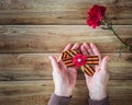 Concept background of May 9 russian holiday Victory Day. Old woman holding in hands a red carnation and St. George`s ribbon. Flat Royalty Free Stock Photo