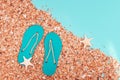 Concept of beach holiday. Sand Beach and and summer slippers, small starfishes on bright paper background Royalty Free Stock Photo