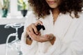 Young adult afro american woman in bathrobe spending morning in bathroom