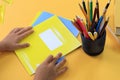 The concept of the beginning of school classes. The child`s hands hold yellow notebooks on the background of a table with school