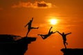 The concept of betrayal and the help of friends, Silhouette of Men are jumped between high cliff at a red sky sunset Royalty Free Stock Photo