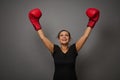 Concept of blow to prices on gray background with copy space. Woman boxer in black medical protective mask and boxing gloves Royalty Free Stock Photo