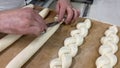 Professional baker`s hand gathering the dough and creating the loaves of bread, and with the other hand cutting the dough with th Royalty Free Stock Photo