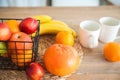 Concept breakfast made from fruits and coffee or tea. Oranges, bananas, cups, peaches on a textural large wooden table against a b