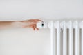 Woman hand turning regulator knob on heating radiator in room Royalty Free Stock Photo