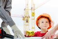 Concept, builders are discussing with child over drawing. Helmet protective equipment construction city site, cranes Royalty Free Stock Photo