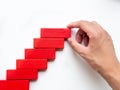 Concept of building success foundation. Women hand put red wooden block in the shape of a staircase Royalty Free Stock Photo