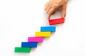 Women hand put red wooden block on colorful wooden blocks in the shape of a staircase Royalty Free Stock Photo