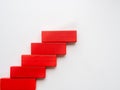 Concept of building success foundation. Women hand put red wooden block in the shape of a staircase Royalty Free Stock Photo