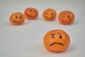 Concept of bullying, discrimination. Group of laughing emoticon faces and one alone look sad and depressed. Lemmons and mandarines