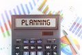 On the table are financial charts and a calculator, on the electronic board of which is written the text - PLANNING