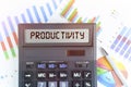 On the table are financial charts and a calculator, on the electronic board of which is written the text - PRODUCTIVITY