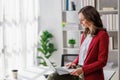 Concept of business working, Businesswoman wearing red suite sitting on her desk while using computer laptop for checking business Royalty Free Stock Photo